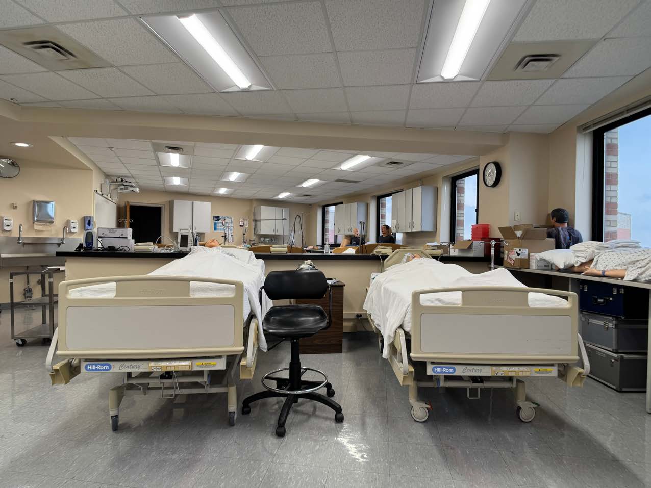 Nursing Department Lab Photo of a nursing department classroom with two hospital beds containing medical dummies and a couple of students in the background.